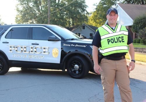 Officer with vest next to car